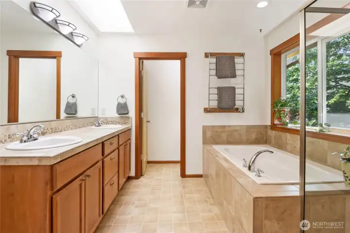 Sky-lit primary bath with dual sinks, separate water closet, & luminous skylight.