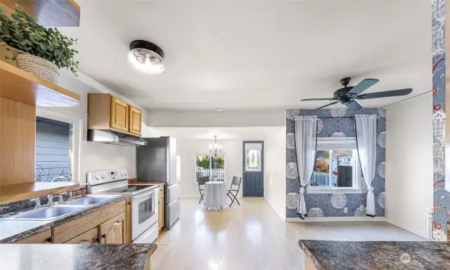 From the dining area, this angle showcases the kitchen’s efficient layout, complete with modern light fixtures, beautiful wood cabinetry, and a neutral design palette that will complement any style.