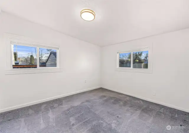 Relax in this tranquil bedroom, where large windows frame peaceful views and provide abundant natural light. The neutral tones and plush carpeting create a cozy retreat for restful nights.