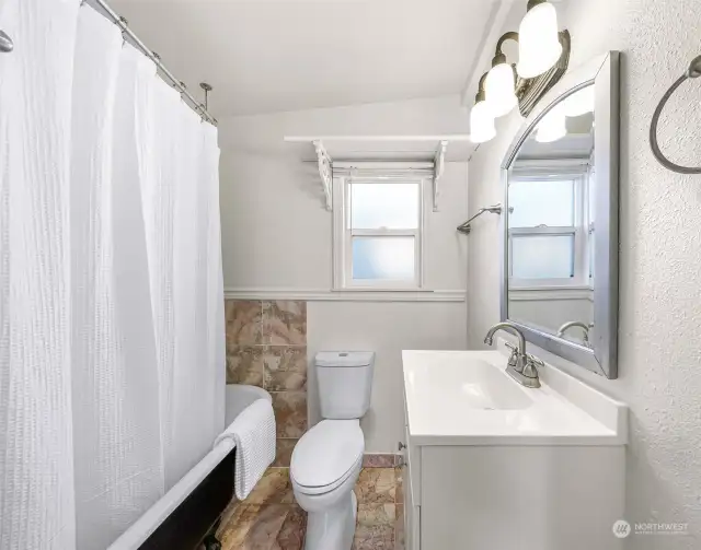 The recently updated bathroom features a sleek vanity with modern fixtures and bright lighting. The window adds charm and provide natural light, creating a welcoming space to start your day.