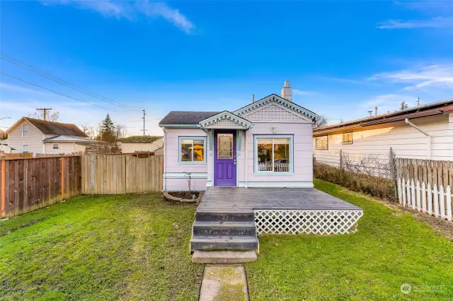 This view emphasizes the charm of the large, fully fenced front yard. The classic white picket fence complements the cottage’s aesthetic and offers a secure space for pets, gardening, or enjoying the outdoors.