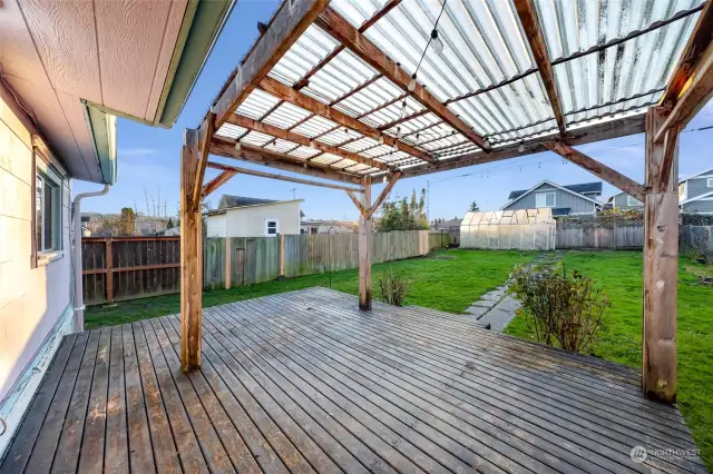 A welcoming covered back porch with a wooden deck, perfect for relaxing or entertaining outdoors.