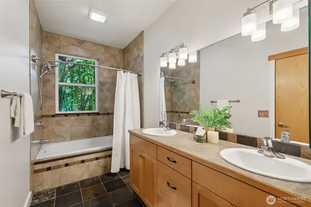 Primary bathroom with double sinks, jetted tub, new light fixtures, and quiet fan.