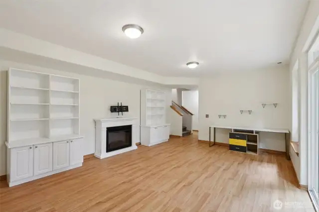 The lower level includes a versatile rec room with a built-in desk, electric fireplace, shelving, and a TV-ready mount.