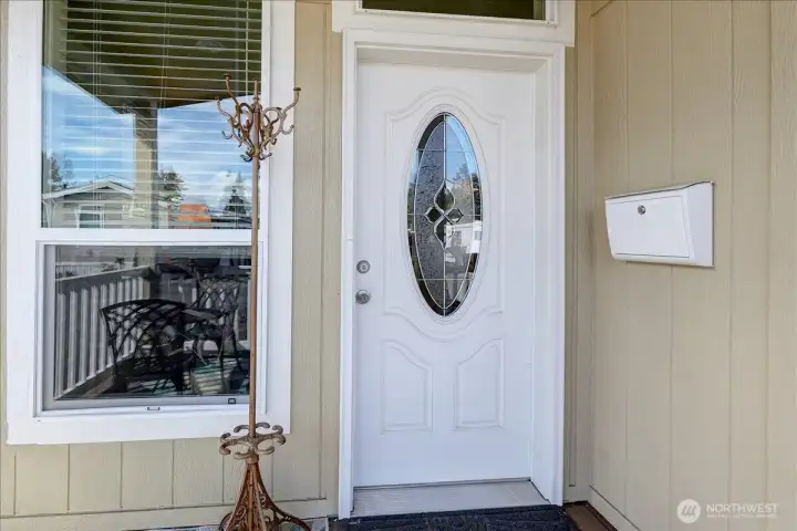 Welcome home to this charming entrance, featuring a classic white front door with an elegant oval window. The entryway is designed to make a great first impression, with a stylish wall-mounted mailbox and a large window that brightens the porch. This inviting space is the perfect introduction to the comfort and style found throughout the home.