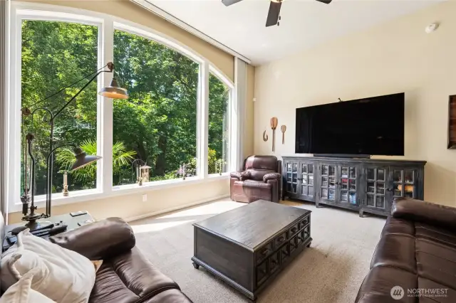 Impressive living room with vaulted ceilings and a stunning wall of windows framing lush greenery.