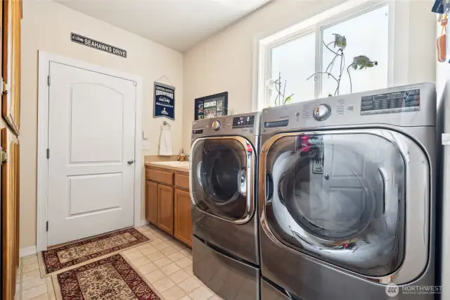 Laundry room includes utility sink, cabinetry storage & direct garage entry.