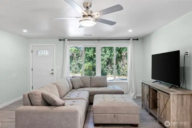 Living room has large vinyl windows, vinyl plank flooring and ceiling fan to keep you cool in the summer.