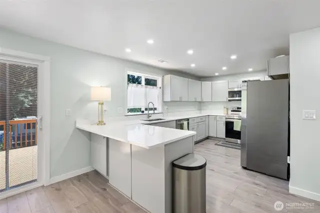 Beautiful, like new kitchen with light toned upper and lower cabinets, white countertops and stainless appliances and small breakfast bar.