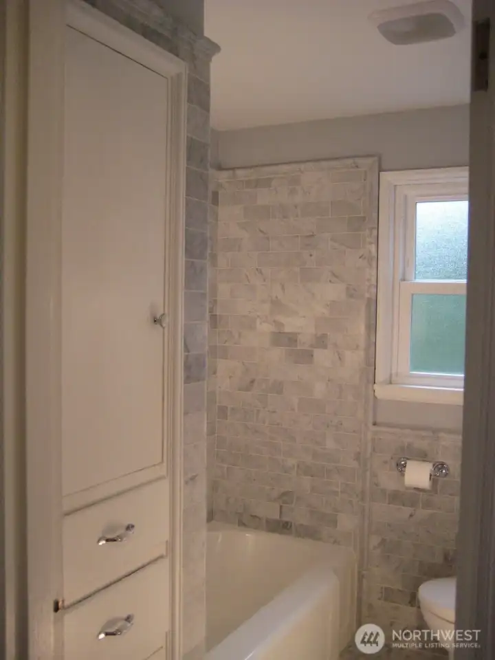 Main level bath with Carrara marble. Built-ins for convenient storage.