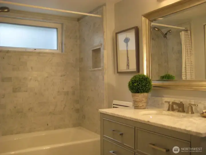 Lower level bathroom with Carrara marble and soap niche.