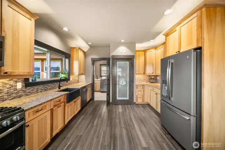 The kitchen has custom cabinetry, granite countertops, and seamless flow into the dining room and main living space