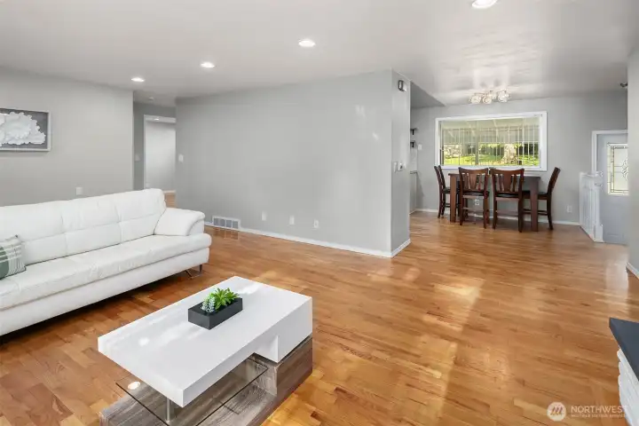 The living room connects to the dining and kitchen area The door to the backyard can be seen on the right, along with the stairs to the upper and lower levels.