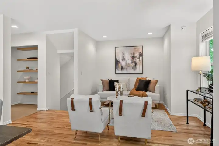 View of the main living area to the stairwell. Sellers had couch and chairs facing window but lots of configuration options. Hall has build-in bookshelfs but could be a pantry or closet. Down the hall is a full main level bathroom for guests.