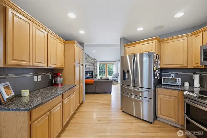 This kitchen features stainless steel appliances, including a double oven, full tile backsplash, beautiful granite countertops, and plenty of workspace for meal preparation.