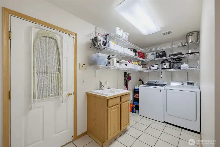 Great sized laundry room offers deep sink, extra storage + door leading out to garage.