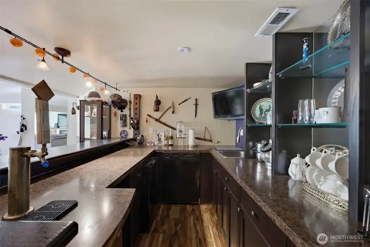 Full wrap around lower level wet bar with Kegerator and tap handle, dishwasher, sink + two beverage fridges.