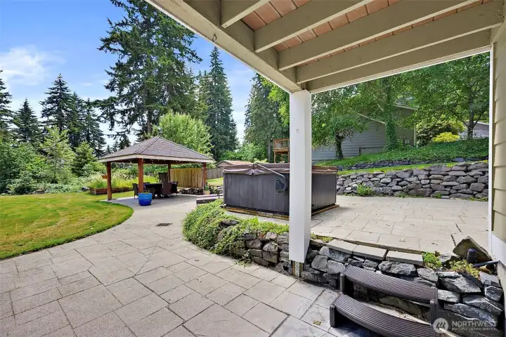Step outside from the lower level bonus room onto the covered paver patio to the hot tub, lawn & gazebo.