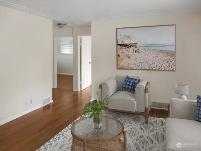 Great open living room space with main floor bedrooms in the background (virtually staged).