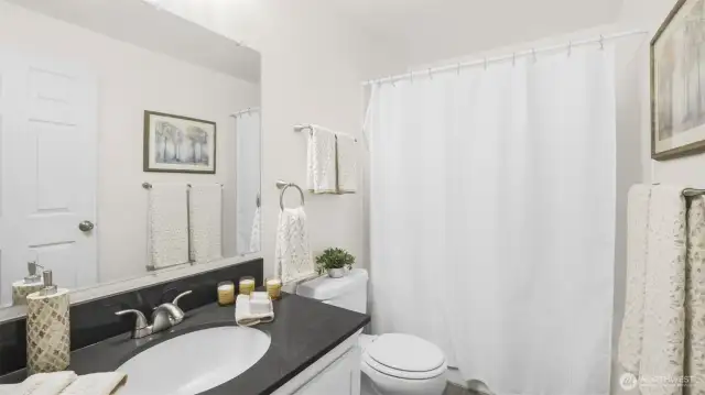 Centrally located full bath with more of the sleek countertops and white shaker cabinetry.