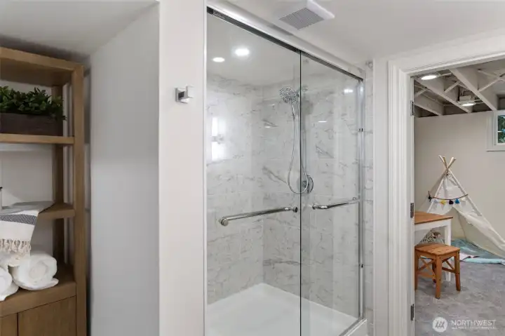 The lower level bath features Carrera design shower surround, 12 X 24 gray tile flooring, Kohler white oak double vanity, chrome fixtures and designer lighting.