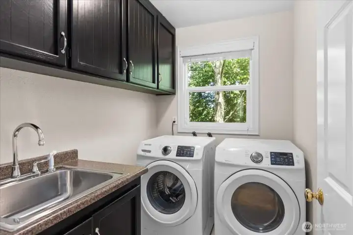 The main-floor laundry provides ultimate functionality with a deep utility sink, upper storage cabinets, and a bright window.