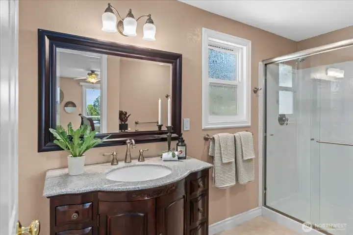 The luxurious bathroom features a large vanity with a granite countertop, jetted soaking tub and a walk-in shower.
