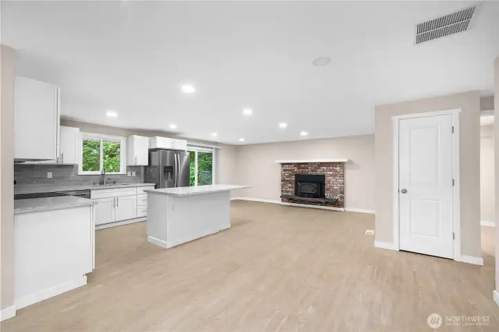 Coming from front living space you are greeted by the brand new, open concept kitchen with cozy wood burning fireplace. Easy access to the slider invited indoor-outdoor living. Laundry room is directly to the right of the coat closet depicted here.