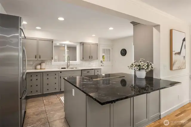 Generously sized chef’s kitchen with SS appliances, quartz countertops, abundant storage, and oversized island centerpiece.