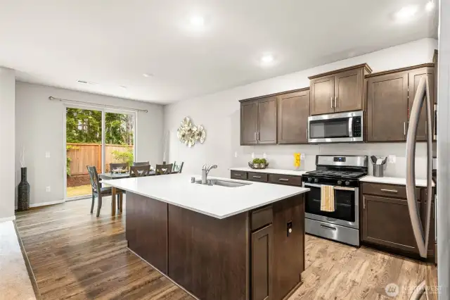 Bright and open kitchen with expansive island, stainless steel appliances, and seamless access to the fully fenced backyard—perfect for indoor-outdoor living