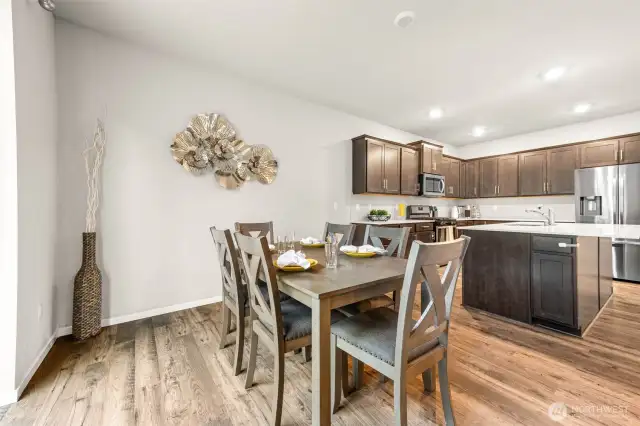 Open-concept kitchen and dining area blends warmth and functionality with rich cabinetry, a large quartz island, and seamless flow—perfect for everyday living and effortless entertaining.