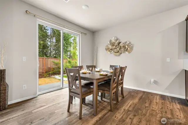Enjoy meals with a view in this light-filled dining area, featuring beautiful wood-look flooring and easy access to the backyard oasis through oversized sliding glass doors