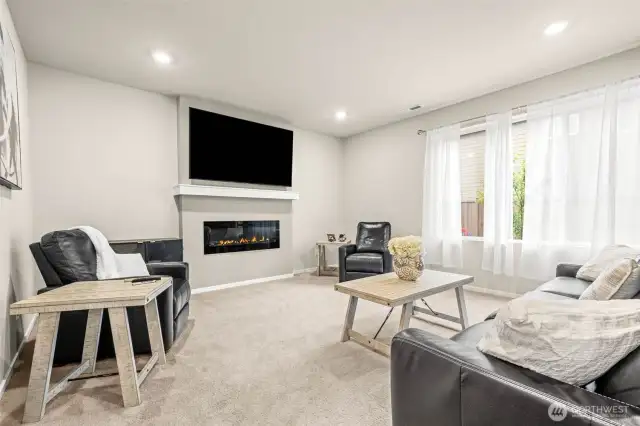 Cozy yet modern living room with a sleek linear fireplace, large window for natural light, and a welcoming layout ideal for relaxing or entertaining