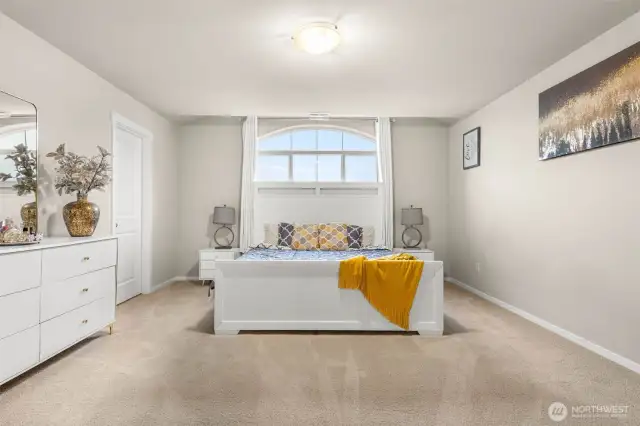 Retreat to your spacious primary suite filled with natural light, highlighted by a dramatic arched window and neutral tones that create a calming atmosphere.