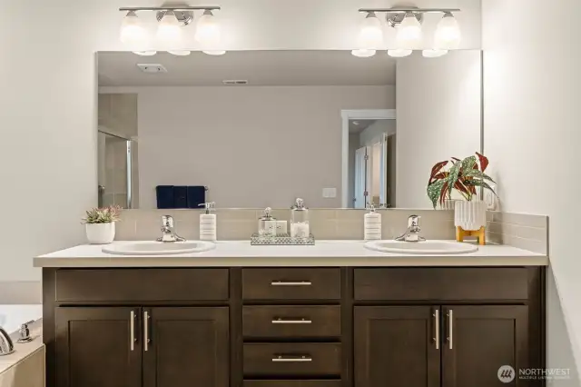 The spa-like ensuite bath features a dual-sink vanity with rich cabinetry, updated lighting, and ample counter space—perfect for busy mornings or relaxed evenings