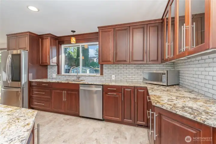 The beautifully updated kitchen features rich dark-toned cabinetry, stainless steel appliances, an oversized peninsula, and abundant counter space and storage.