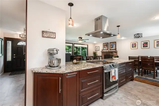 The beautifully updated kitchen features rich dark-toned cabinetry, stainless steel appliances, an oversized peninsula, and abundant counter space and storage.