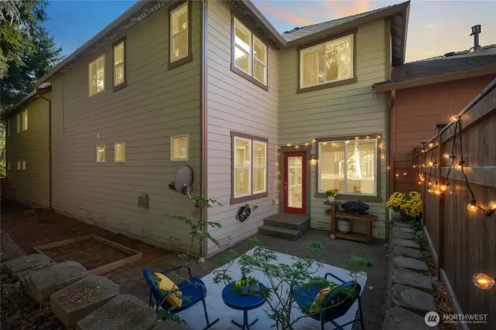 Outdoor seating area perfect for morning coffee, with paved patio, and backyard with garden beds.
