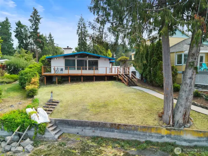 6 steps down to the beach from  your front lawn.  Expansive deck for enjoying the marine views.