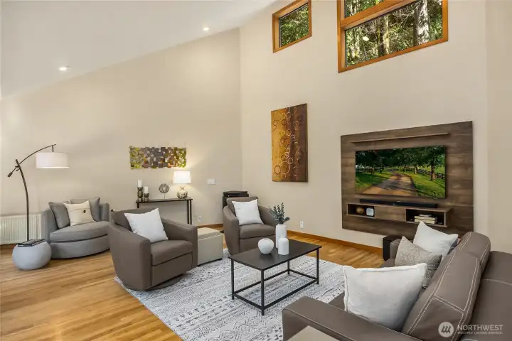 Dramatic windows in the living room bring in lovely light and pretty views from the natural surroundings.