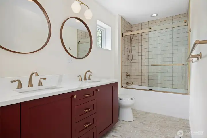 Full upper bath with custom tile work, wood cabinetry and dual sinks.