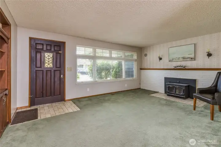 Living room with wood fireplace insert and built-in shelving. All windows are triple-pane!