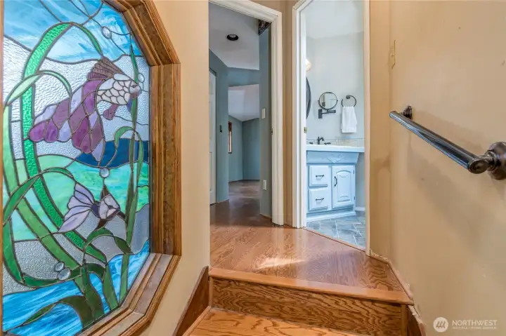 Hallway leading to the primary suite features this custom stained glass window