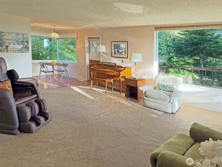 The living room flows into the eating area, allowing you to extend the eating area as large as you'd like to for special occassions. Piano can remain with the house. The door in the photo is access to the deck and back yard.