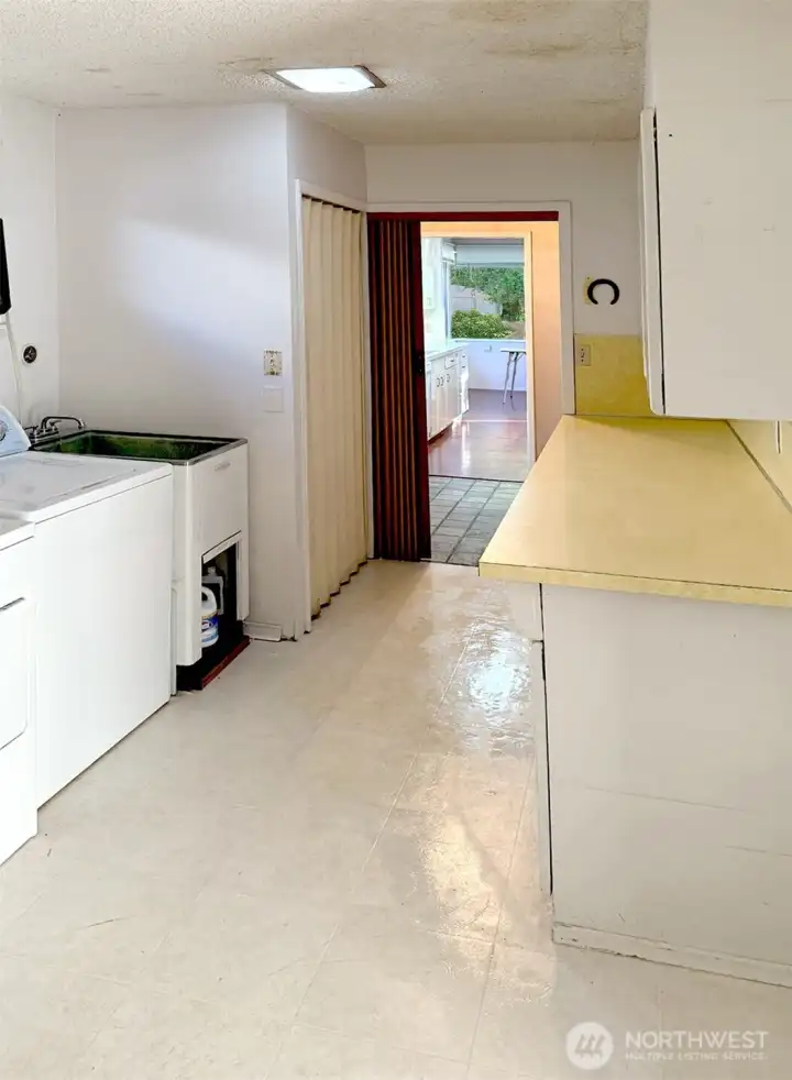 Here you can see the laundry area with a large sink and closet. This shows how close these cupboards and counter are to the kitchen. It's very handy to have the laundry room on the main floor so you don't need to carry it down and back upstairs.