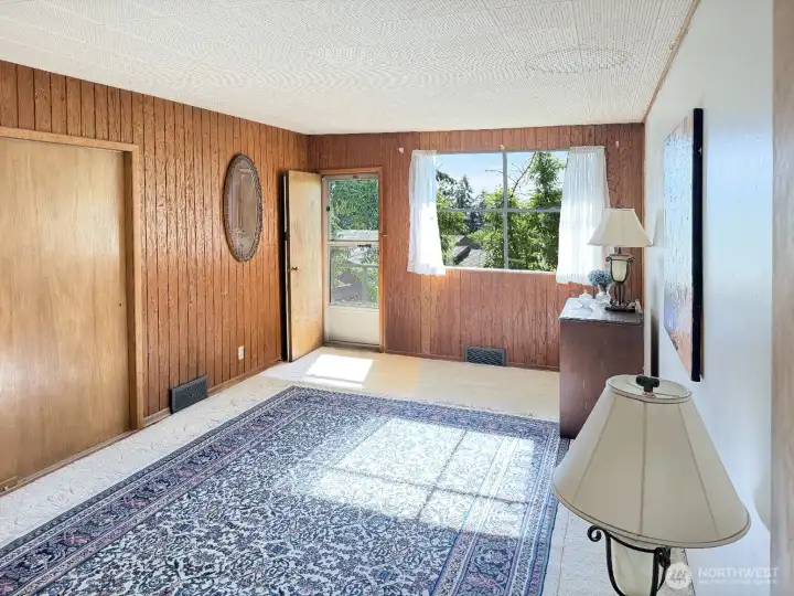 The spacious, primary bedroom with access to the west facing deck. How nice to allow fresh air into the roon during the day and or for sleeping. The paneling and closet doors are original. This is the only room known to have hardwood floors under the carpet. The carpet has been in place for many years. The condition of the hardwood floors are unknown.