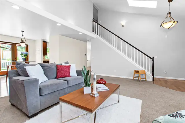 Cozy living room with vaulted ceiling, adjacent to formal dining area.