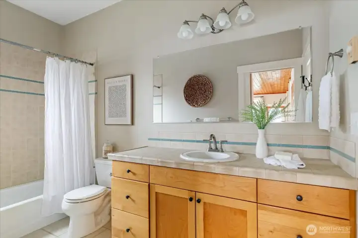 Primary bath functions as a shared bath, door to primary is on right, and door to the rest of the house is reflected in the mirror.