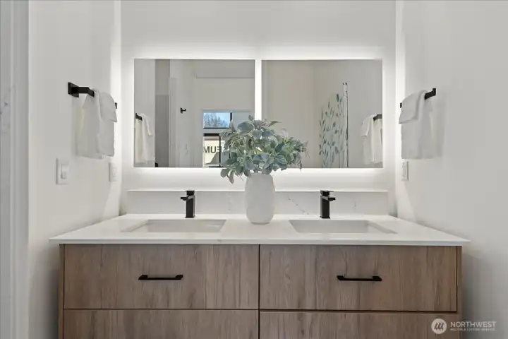 The primary bathroom features a double vanity and beautiful backlit mirrors