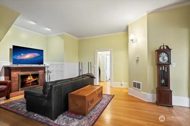 The living room is anchored by a majestic brick fireplace. The wood floors are original.